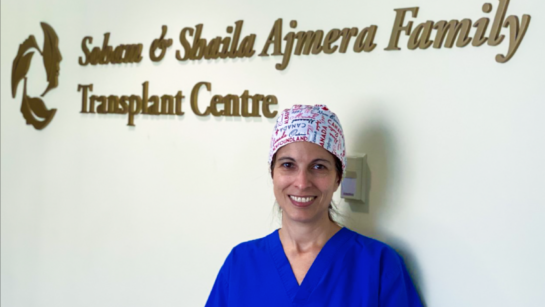 Photo of Teresa Torres standing in front of the Soham & Shaila Ajmera Family Transplant Centre sign