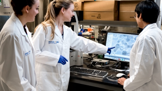 Dr. Stephanie Protze in the lab point at a computer screen with two other scientists around her