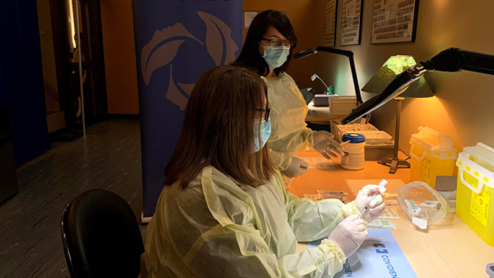 UHN registered pharmacy technician supervisors Tamara Rumsey, (foreground) from Princess Margaret Cancer Centre, and Francesca Pasceri of Toronto Rehab, prepare the vaccine for administration Monday at The Michener Institute of Education at UHN. (Photo: UHN)