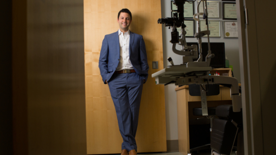 Dr. Efrem Mandelcorn smiling and leaning against a wooden office door