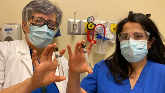 UHN's Yas and Stella holding vials with PPE.