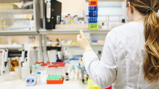 Female scientist with her back turned to the camera working on an experiment in the lab.