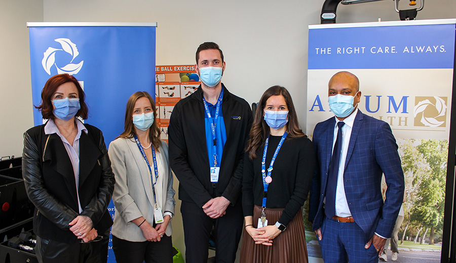Five Altum Health employees stand in front of pop-up banners that read: "The right care. Always". They are all wearing face masks.