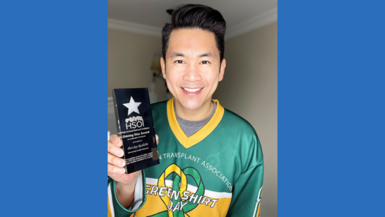 Registered nurse Bee-Jay Realubit holds a Shining Star Award for his work in supporting conversations about organ donation with youth while wearing a Green Shirt Day sweater.