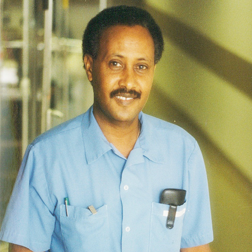 Mohamed Ali smiles as he wears his blue Environmental Services uniform at Toronto General Hospital. 