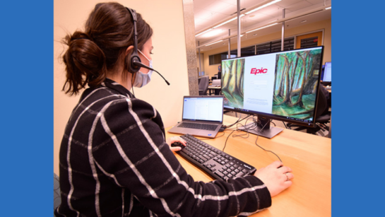 A UHN employee logs onto the new Epic Health Information System with a headset and mask on.