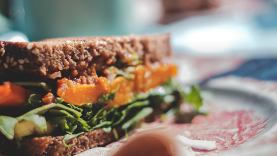 A sandwich on a plate with lots of greens