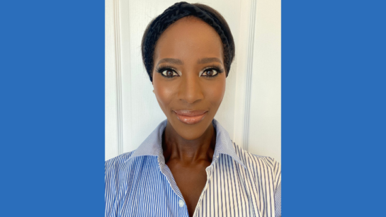 Sharon Munawa takes a selfie while smiling in front of a wall.