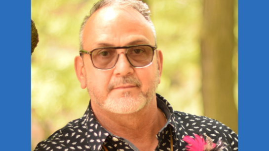 Leonard Benoit wears sunglasses outside in front of nature.