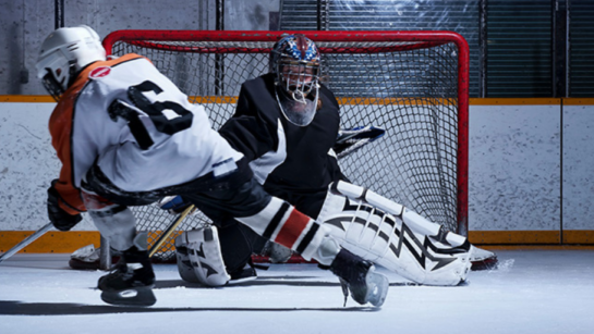 A hockey player trying to score a goal on a goalie