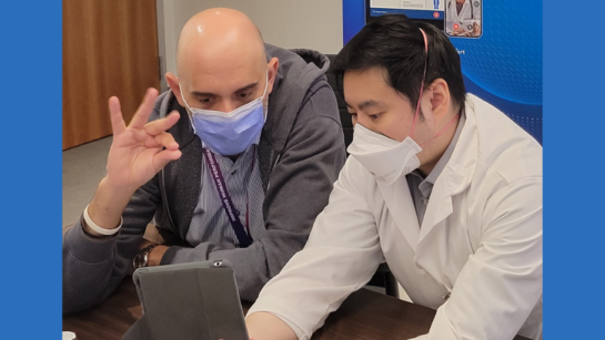 Dr. Alfonso Fasano, (L), and fellow Dr. Wilson Fung consult with a patient remotely