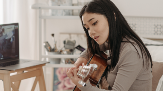 A girl playing guitar while on Zoom.