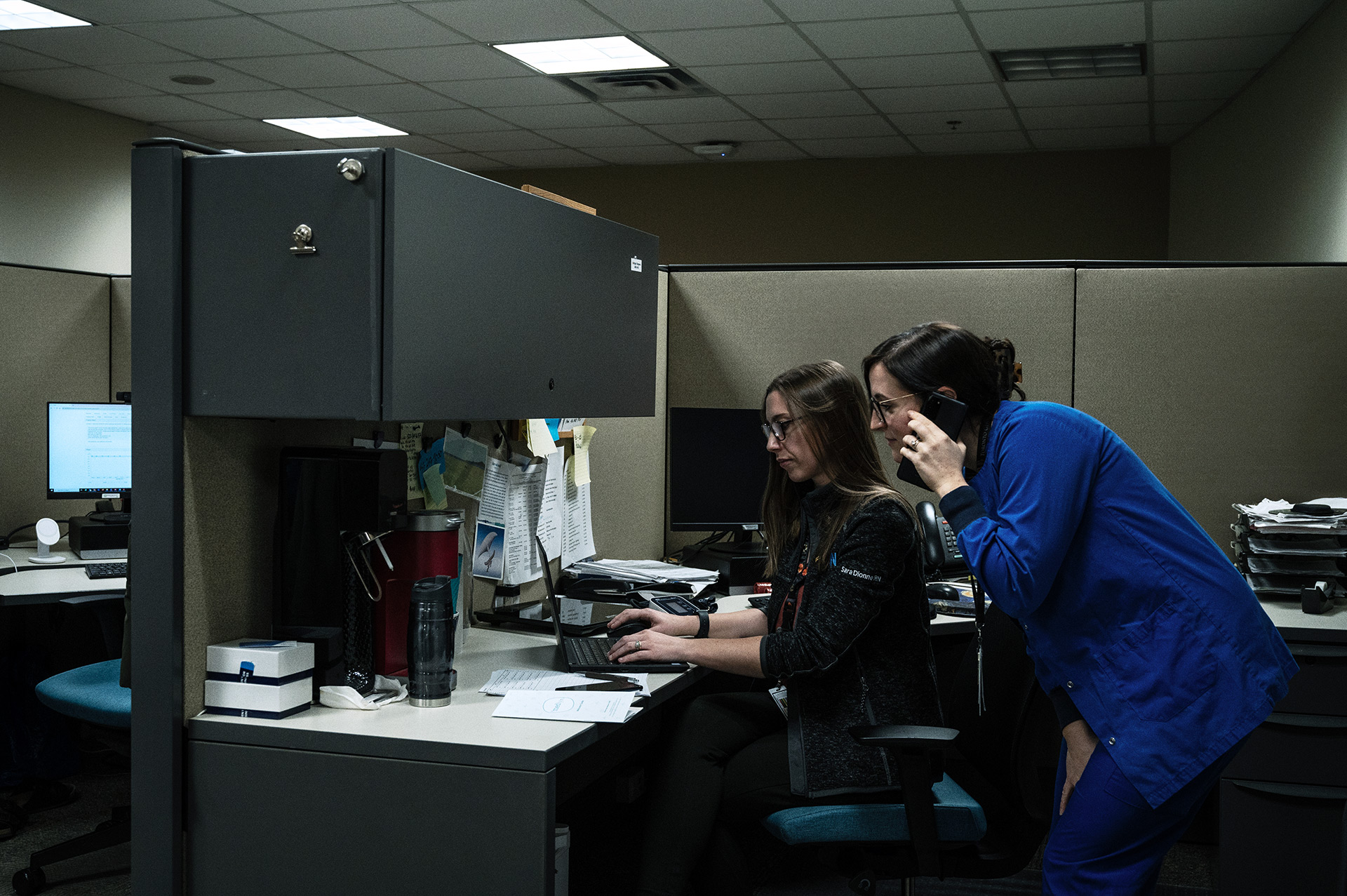 Two nurses at their desk, one of them talking on the phone, inside Toronto General Hospital.