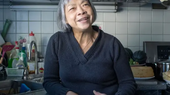 Yee-Bing Wong smiling in her kitchen while cooking