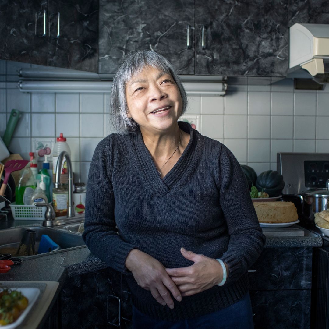 Yee-Bing Wong smiling in her kitchen while cooking