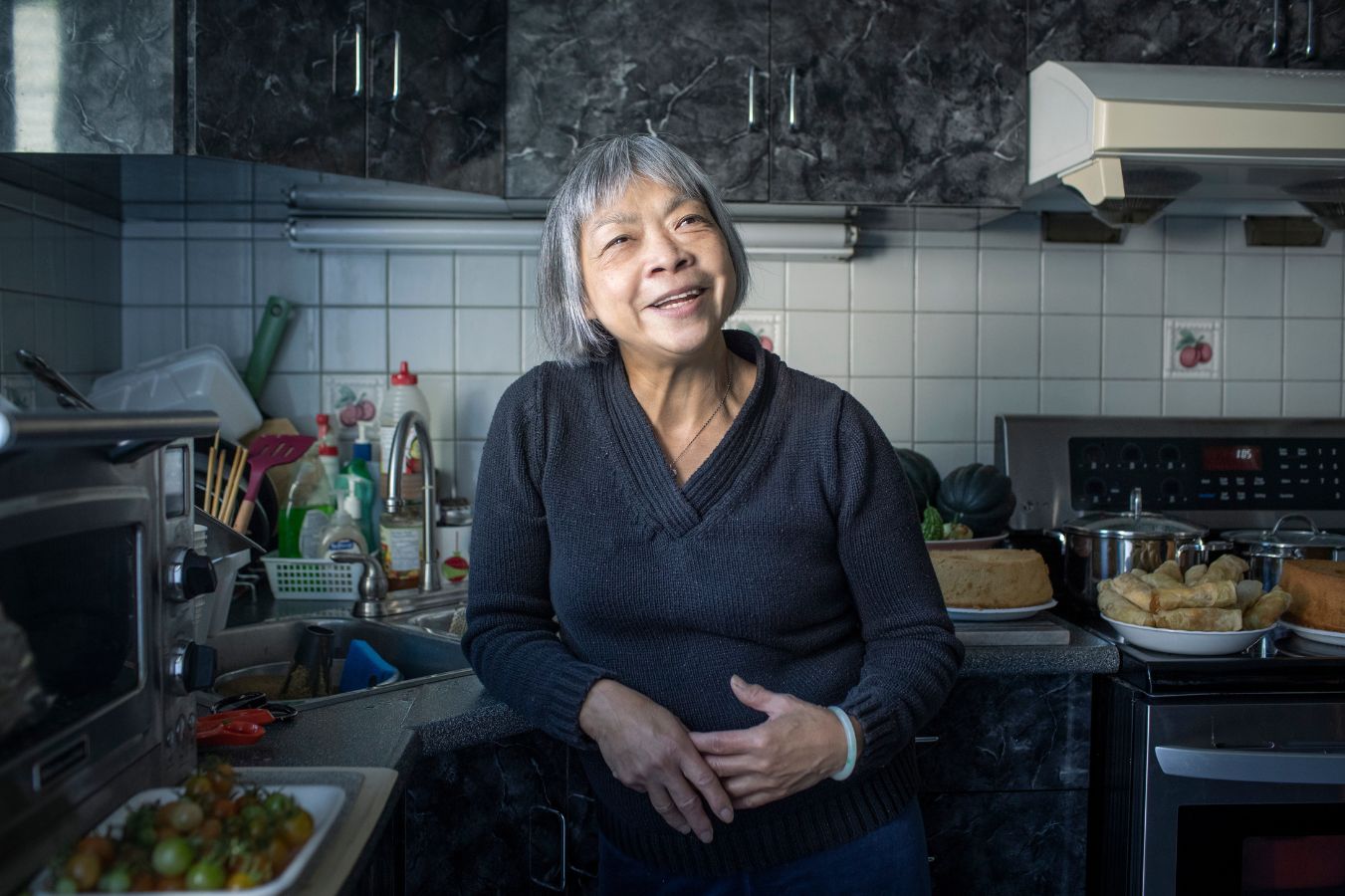 Yee-Bing Wong in her kitchen smiling while cooking