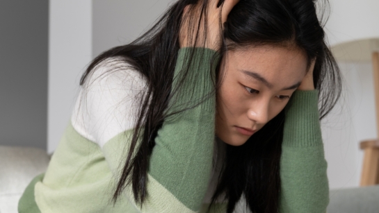 A person holding their head while sitting on a couch with mental fatigue