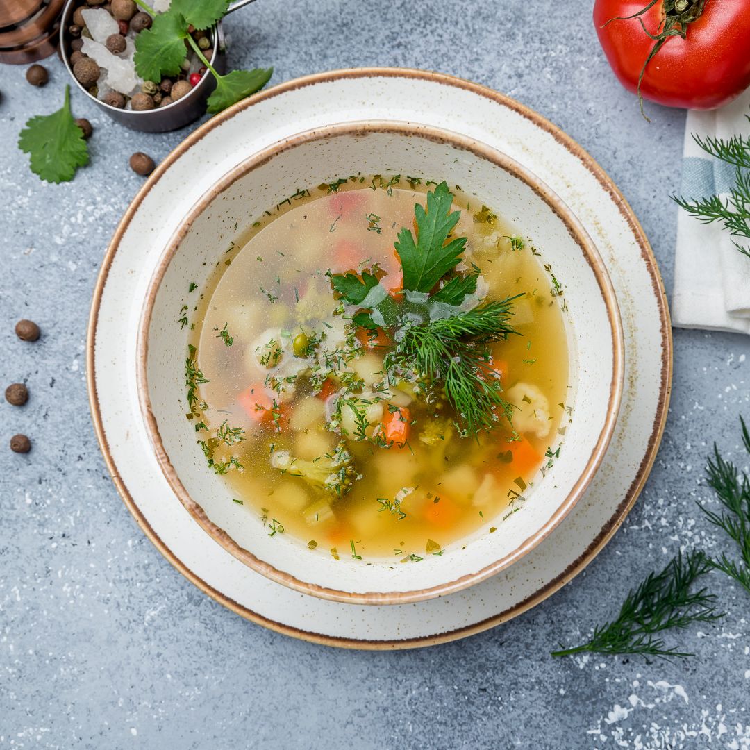 Minestrone soup dish with herbs and a tomatoe