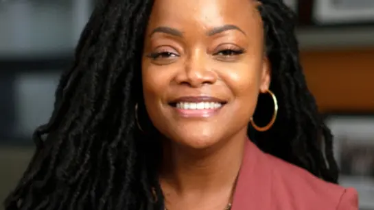 Dr. Nicole Woods smiling in front of a wall of photos