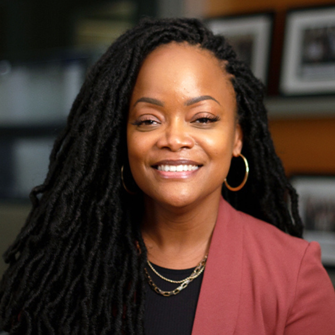 Dr. Nicole Woods smiling in front of a wall of photos