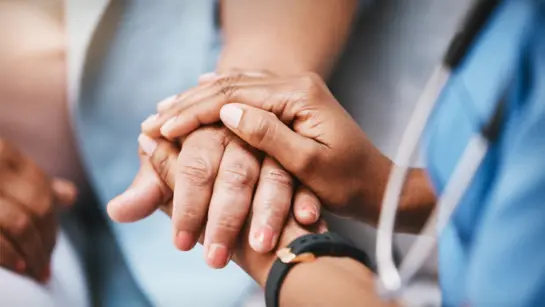 A care provider holding the hand of a patient