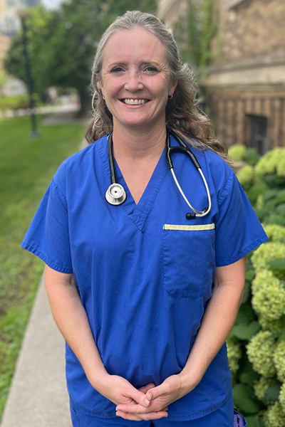 Barbara Bailey standing outside with her UHN Nurse Practitioner outfit on during the summer.