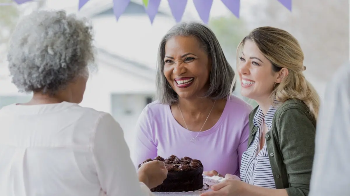 Two fundraisers present a cake to an older lady.