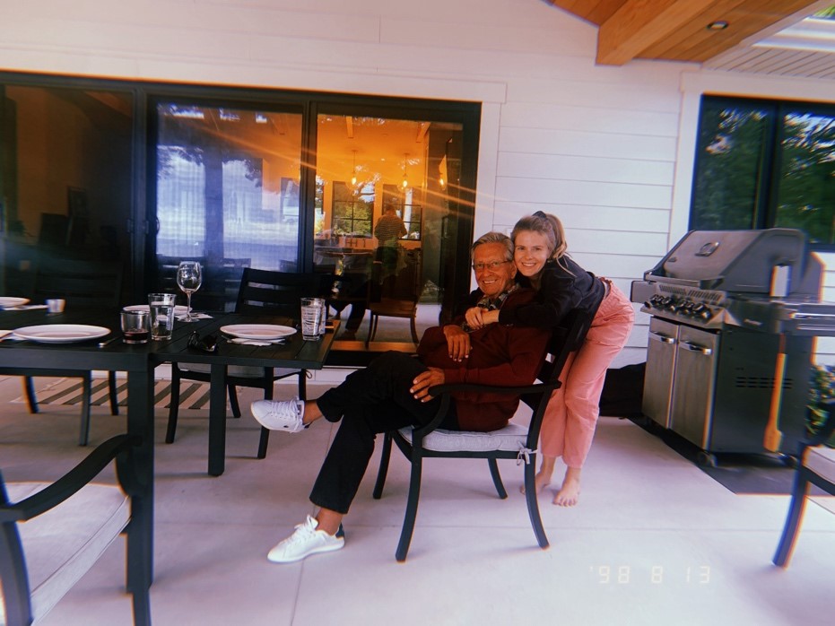 Meredith and her dad days before surgery on their backyard patio with Meredith hugging her father who is sitting at a table