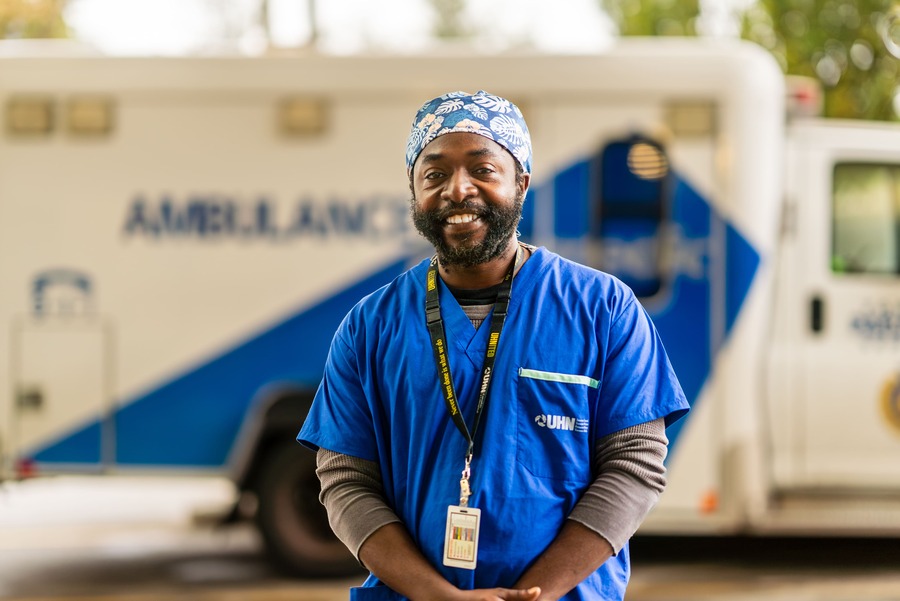 Patrick Esenerwa, peer support worker outside at UHN with an ambulance behind him.