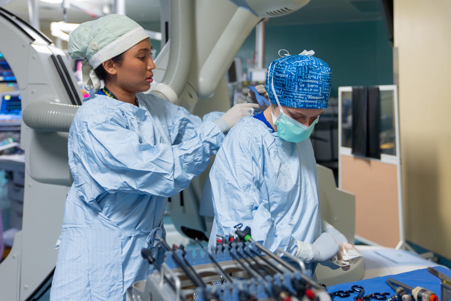 Nurses Zareen Tasneem and Brooke Benetar prepare for surgery in the operating room using AI.