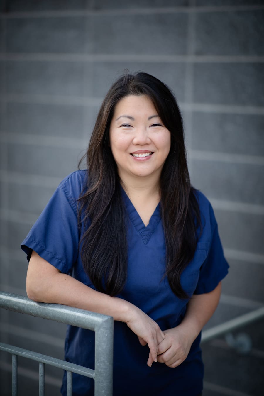 Dr. Clara Chan, a UHN cornea surgeon and researcher smiling while standing on steps next to a railing.