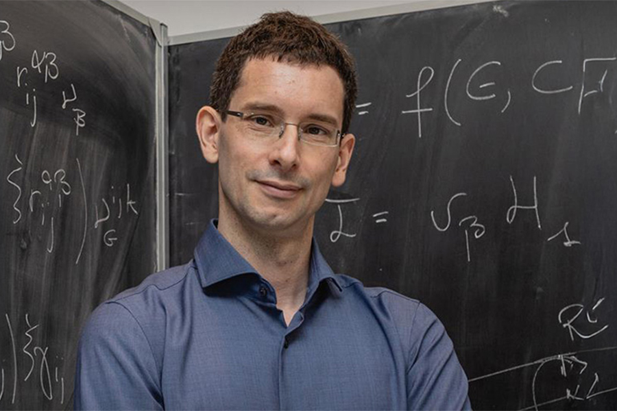 Dr. Maurizio De Pittà in front of a chalk board with formulas written on it.