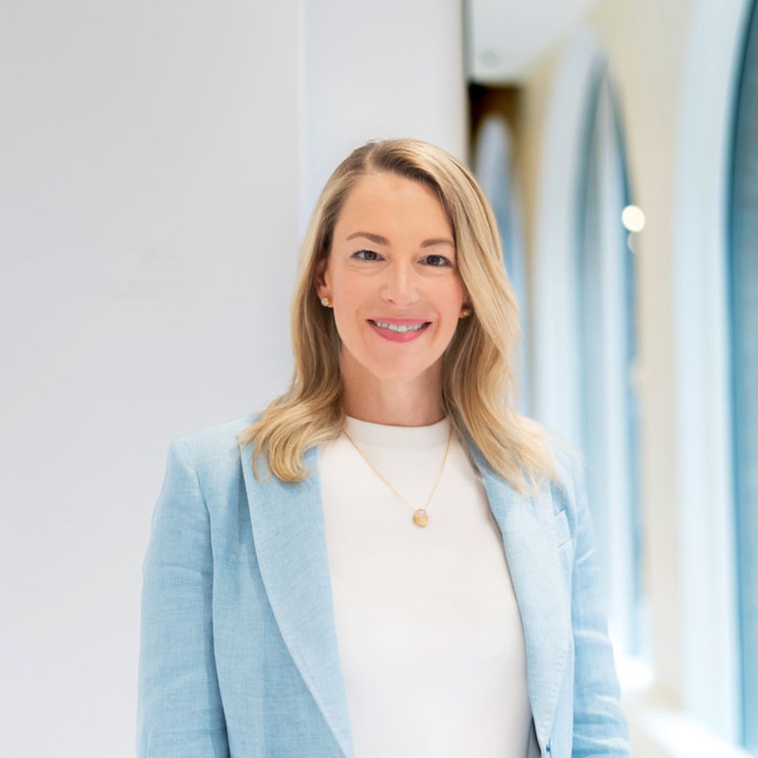 Julie Quenneville smiling in a bright hallway