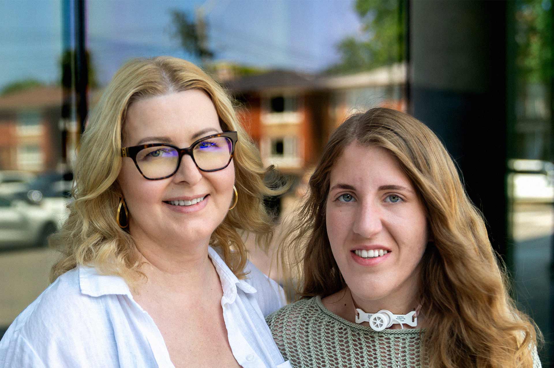 A mother and daughter, smiling, posing for a photo.