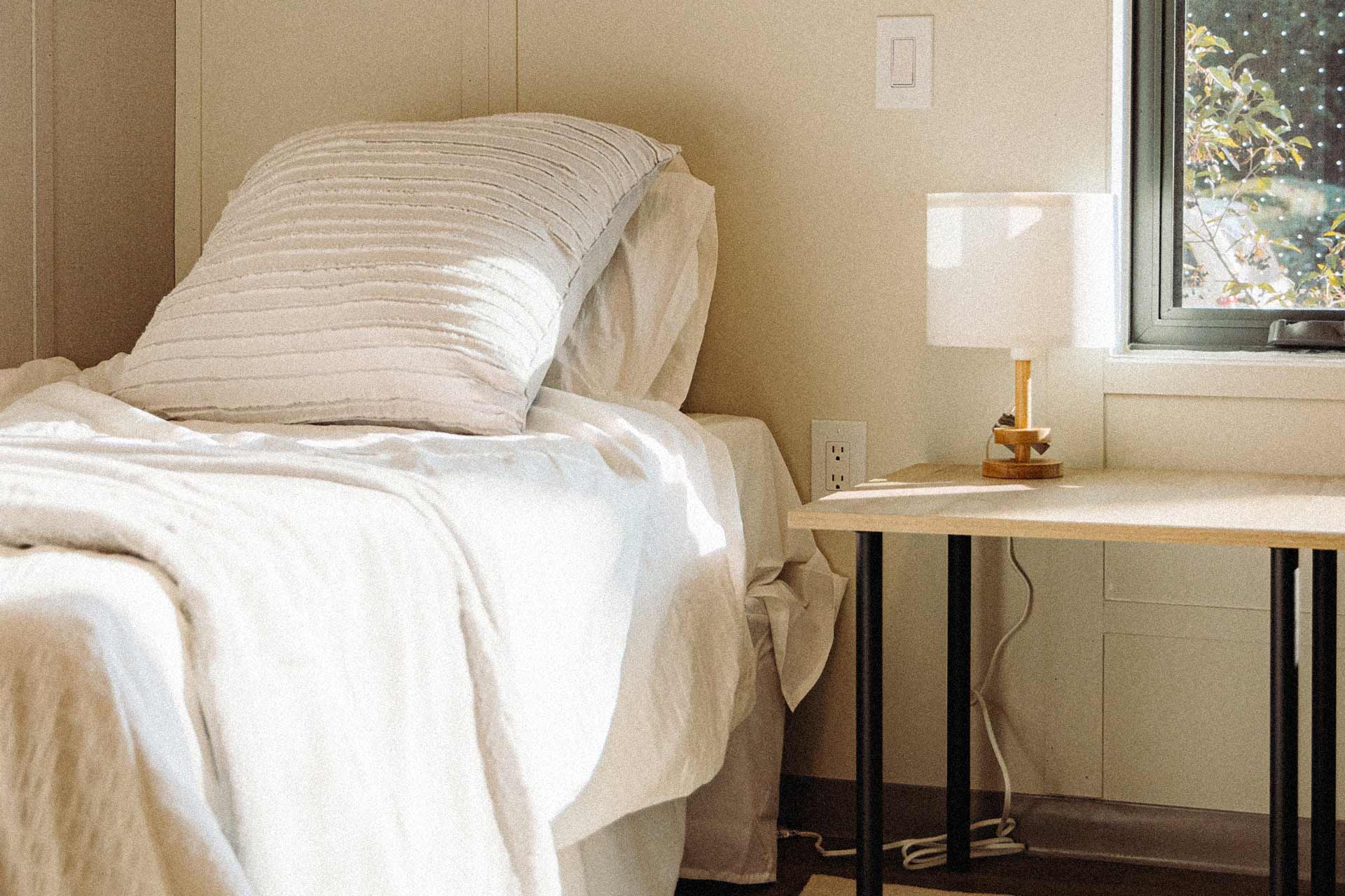 A bedroom with bed, pillow and nightstand.