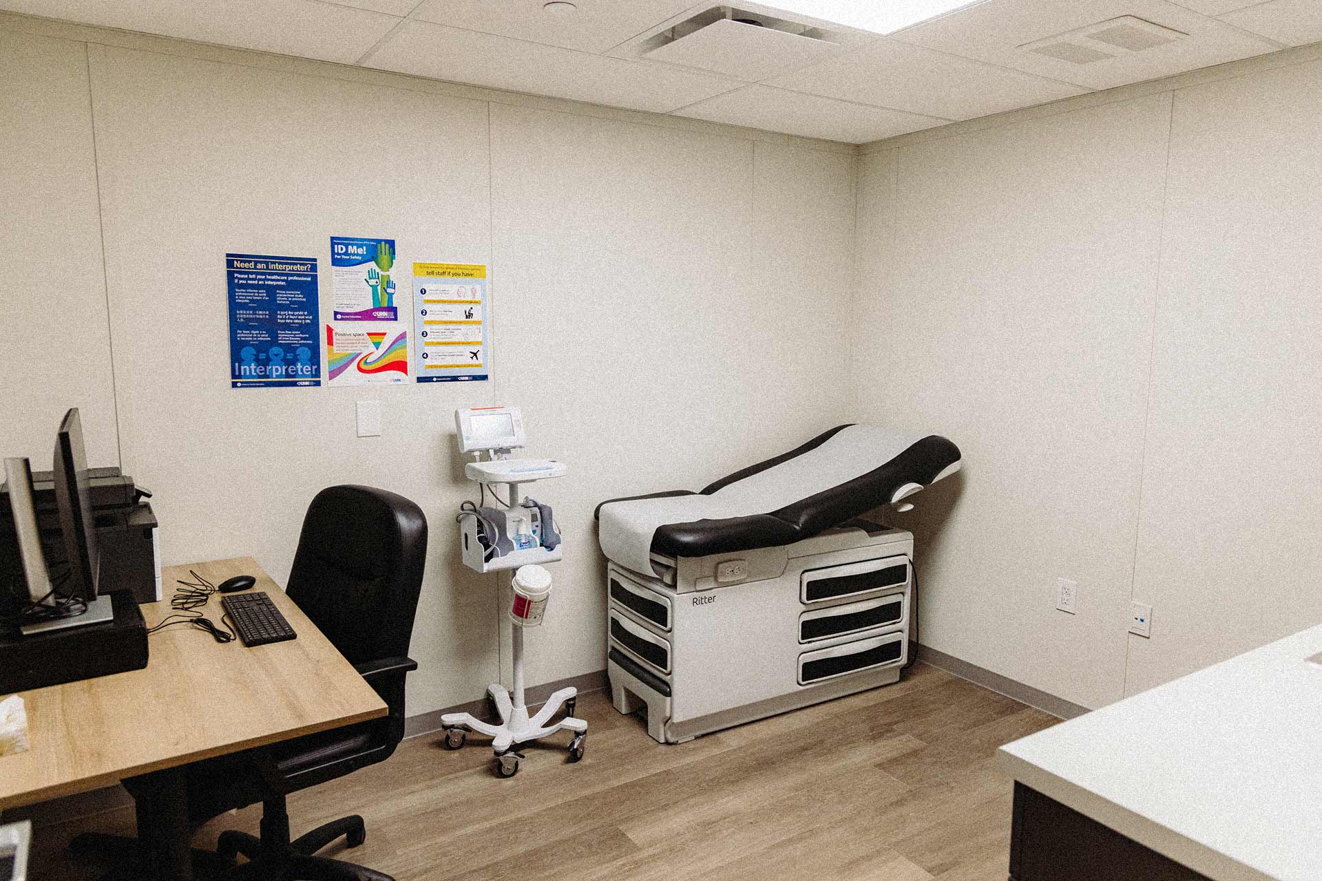 A medical exam room with desk and exam table.