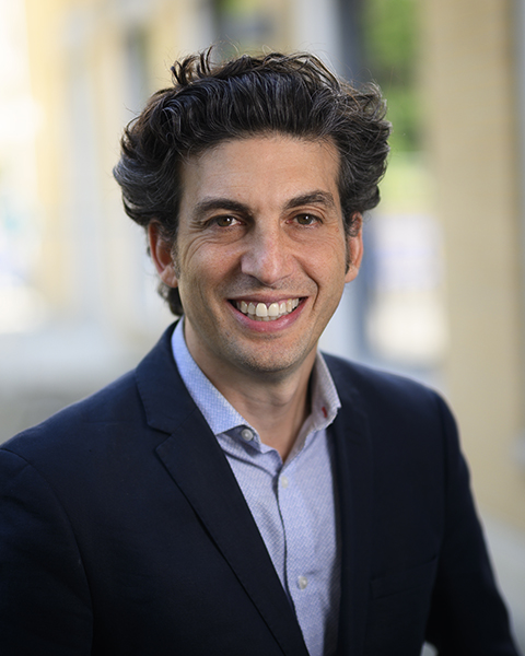 Dr. Jordan Feld smiling in front of a window and wearing a suit.