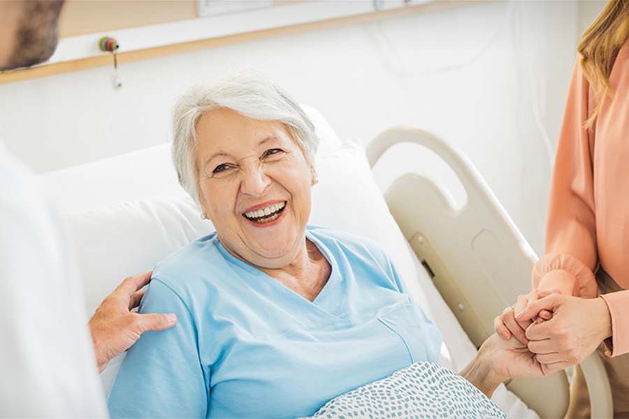 An older woman smiling from her hospital bed.