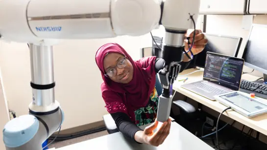 Aisha Raji working on a robotic arm at KITE Research Institute.