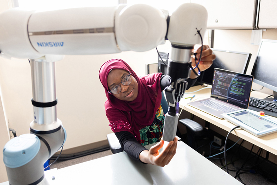 Robot-assisted therapy combines technology and movement to support motor recovery, offering more precise, consistent and personalized care. Aisha Raji, the study's first author, is pictured adjusting a robotic arm used in therapy. (Photo: UHN's KITE Studio)