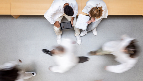Researchers stopped in a hospital hallway as people walk by.