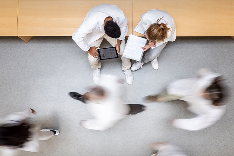A hospital hallway with researchers meeting and sitting down while people walk by.