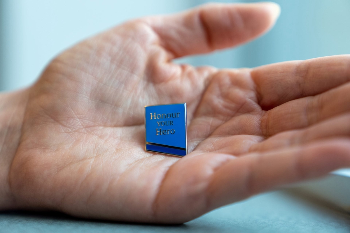 Hand holding an Honour your Hero pin