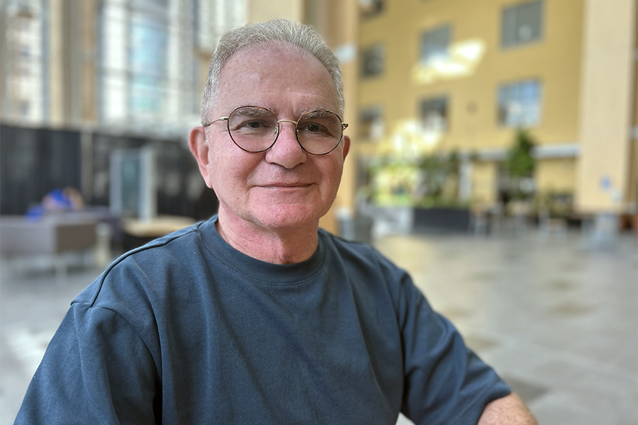 Paul Ross sitting in the atrium at Toronto General Hospital with glasses.
