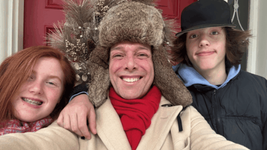 Scott Wilson and his family outside their front door with winter gear on.