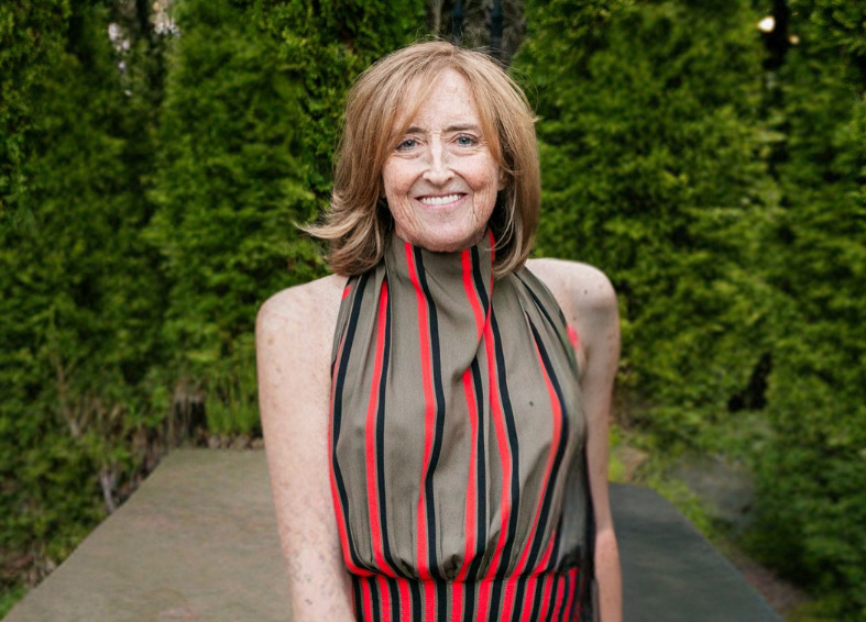 Lynn Francis outdoors next to trees smiling.