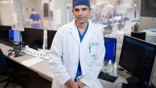 Dr. Sanjog Kalra sitting in front of a surgical room at Peter Munk Cardiac Centre