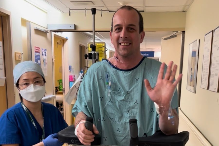 Matt Delorme walking with assistance from hospital staff in the hallways. 