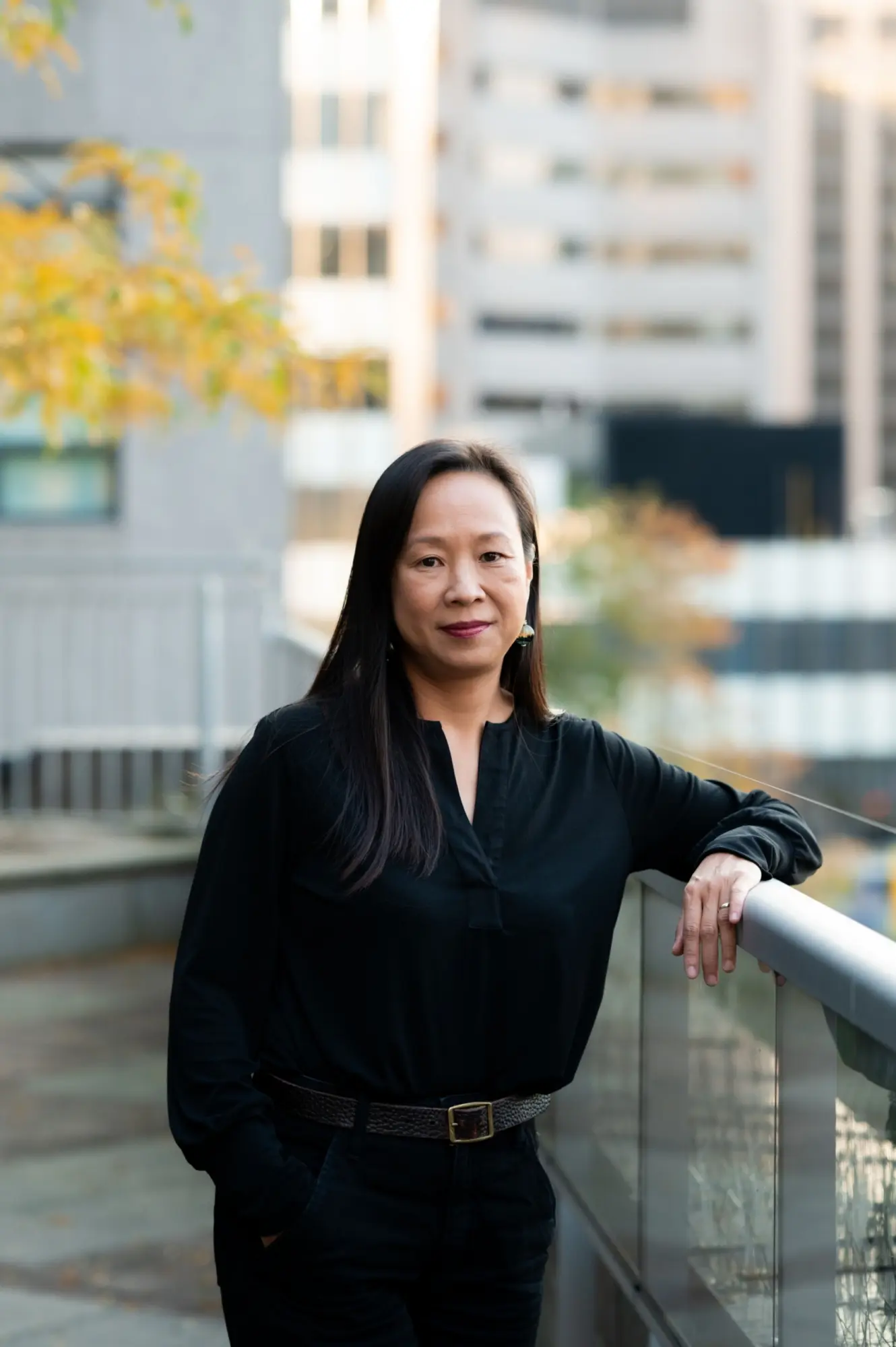 Dr. Esther Bui standing outside of UHN and leaning on a glass railing.