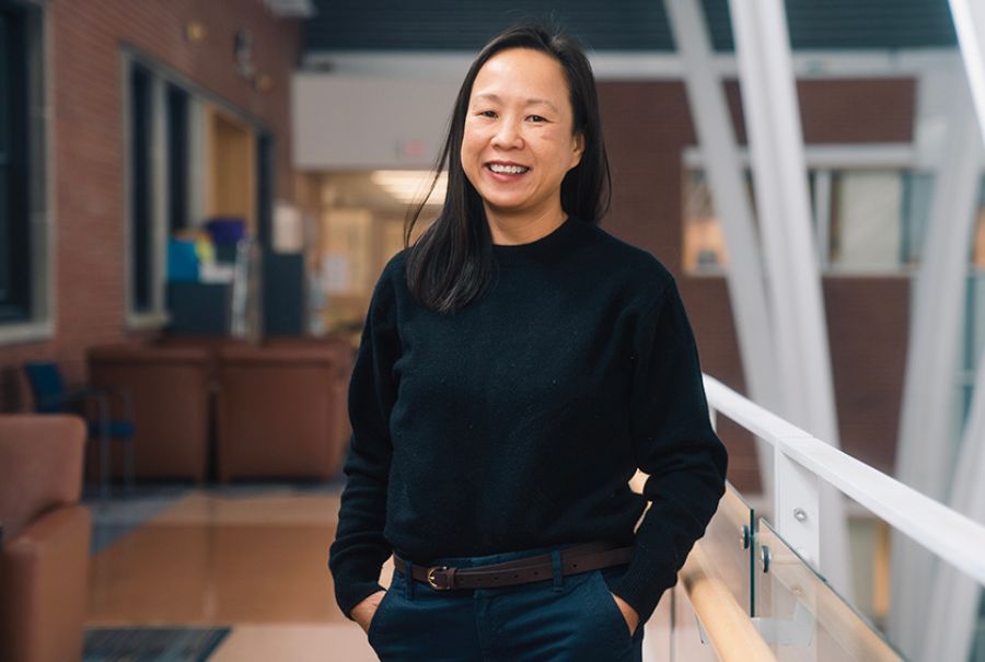 Esther Bui at Toronto Western Hospital with her hands in her pockets and smiling next to a railing.